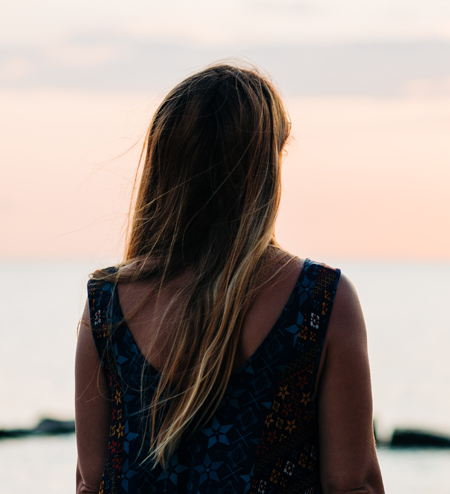 Carol looks away from the camera, towards a beach sunset.