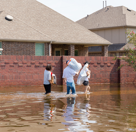 A family carries their belongings through a flooded alleyway.