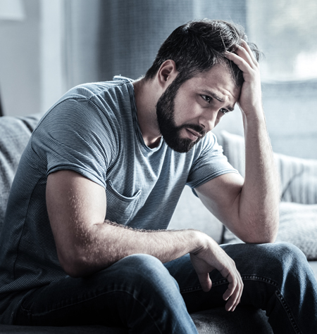 A man looks distressed, holding his head in his hand.