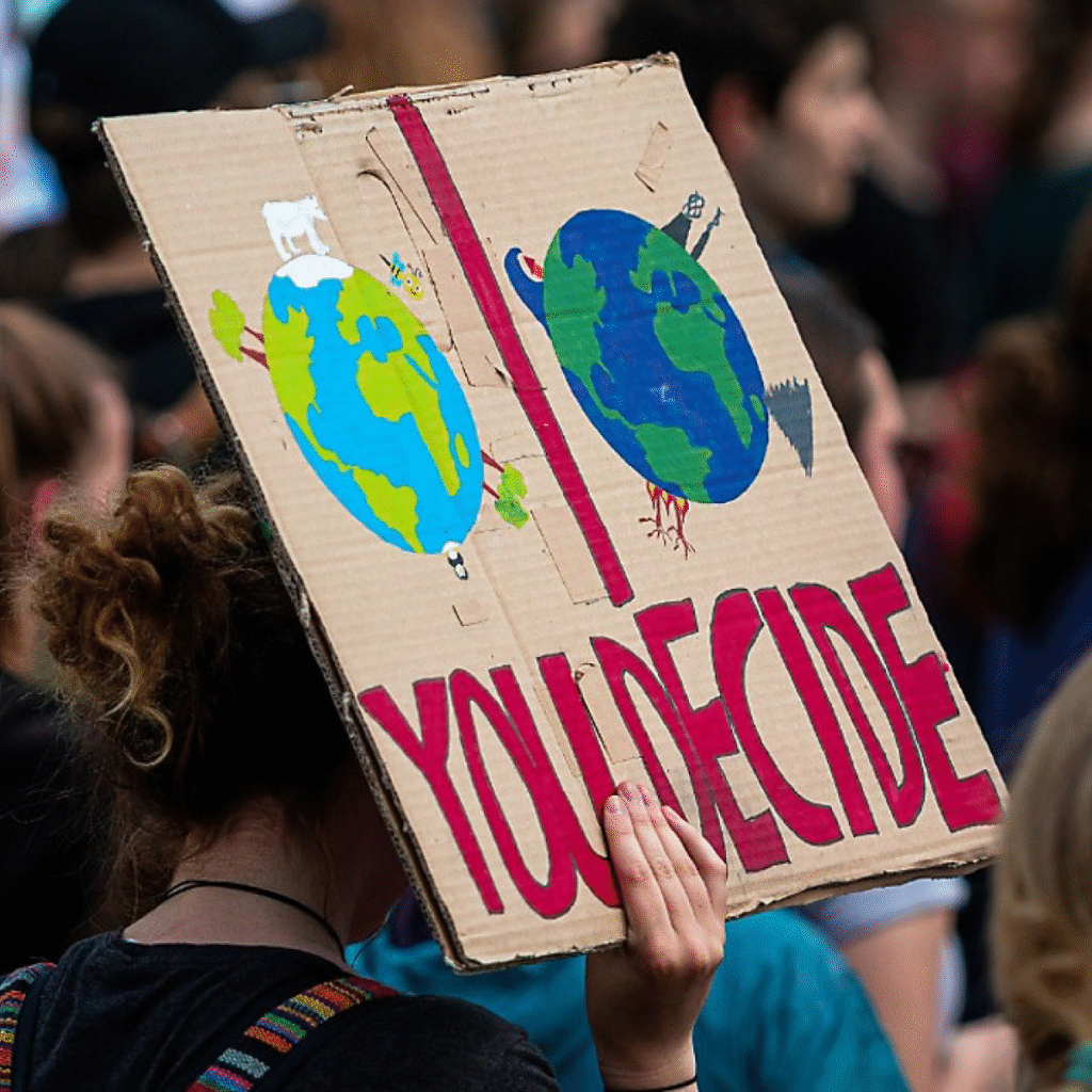 spectrumnews Protestors holding a sign with two versions of the Earth with the words "You Decide"